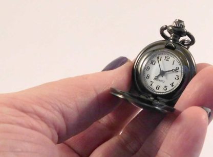 The fob watch in hand showing its small size