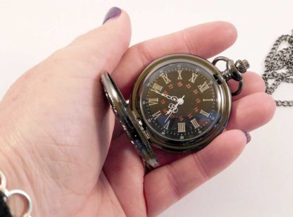 The fob watch in a hand showing the larger size