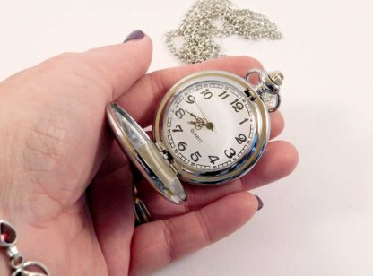 The fob watch is open in a hand showing the size - 5.5cm
