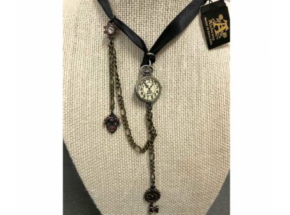 This choker is a clock pendant with 13 hours attached to a black ribbon. A cog key hangs from a chain from the clock and there is separate chain from the bottom of the clock fastening further up the ribbon with a cog and crystal charm