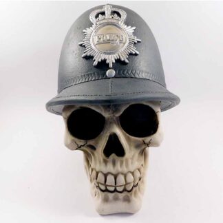 Front view of the moneybox showing the grinning skull and the black old fashioned British police officer helmet decorated with the office police badge
