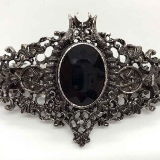 A silver brushed with black hairclip. It has a centre black polished faceted stone, at the top there are devil horns and a crescent moon, to the bottom a pentagram