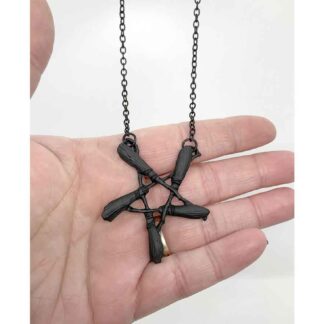 This necklace is made up of tiny black brooms in the shape of an inverted pentagram. The black chain hangs from the two top points